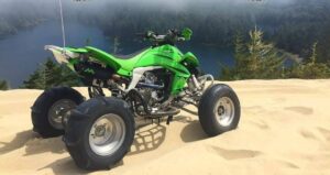Green ATV on sand dune, foggy landscape.